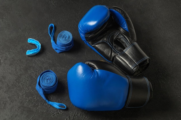 Blue boxing gloves with a cap and bandages on a black background