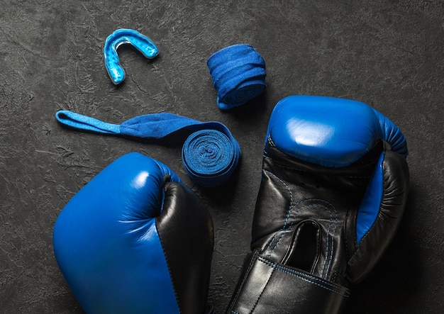 Синие боксерские перчатки с кепкой и бинтами на черном фоне