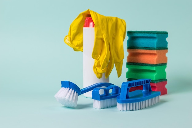 Blue brushes foam sponges cleaning powder and gloves on a blue\
background