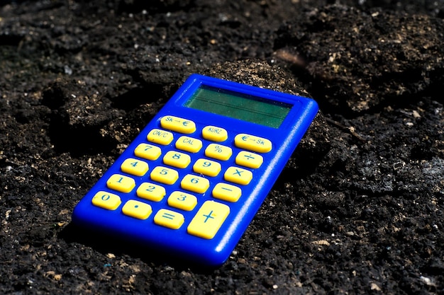 Blue calculator in dark soil burnt ground after the fire