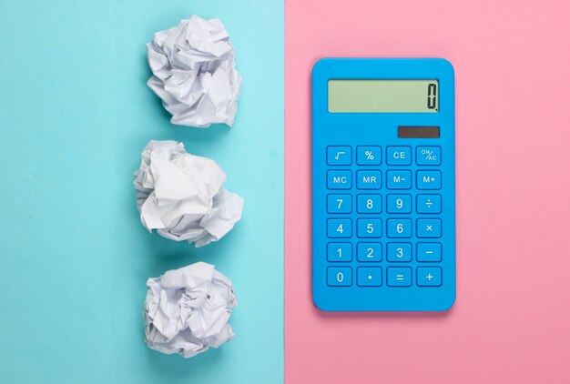 Фото Синий калькулятор со скомканными шариками из бумаги на голубой пастели