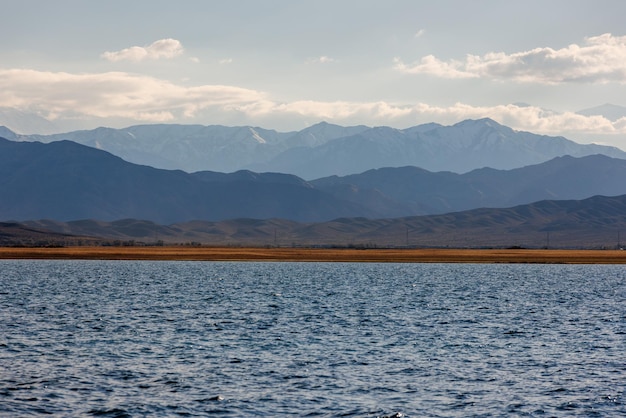 Blue calm water in issykkul lake with mountains on background at autumn afternoon