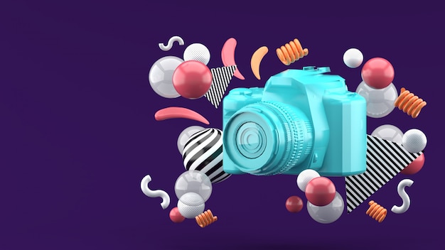Blue camera surrounded by colorful balls on purple. 3d render.