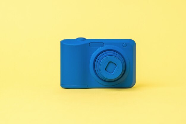 Una telecamera blu con lente retrattile su sfondo giallo. attrezzature obsolete per la fotografia.