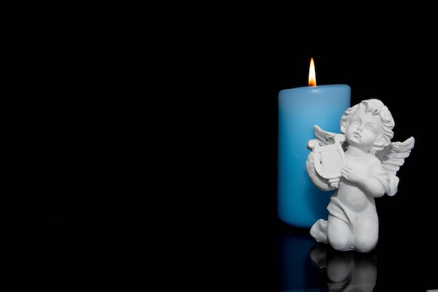 Photo blue candle and angel on black background