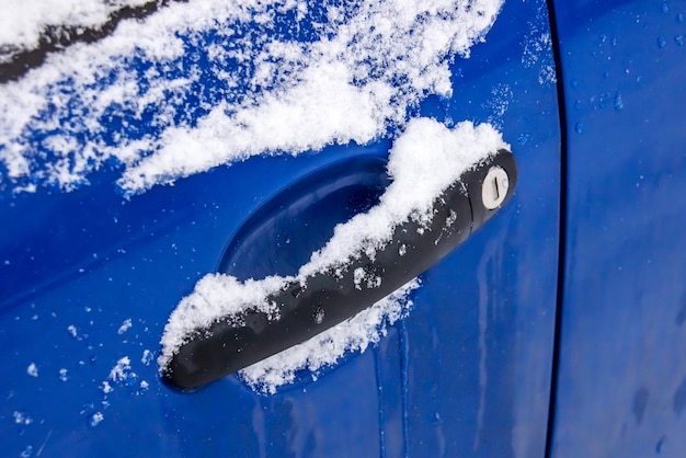 Blue car handle in the snow closeup