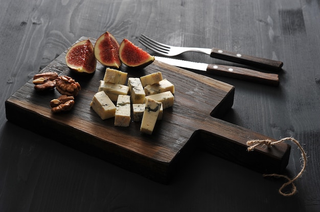 Blue cheese, fresh figs and walnuts on a wooden Board and a knife and fork