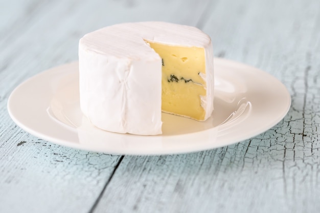 Blue cheese under a rind of white mould on the plate