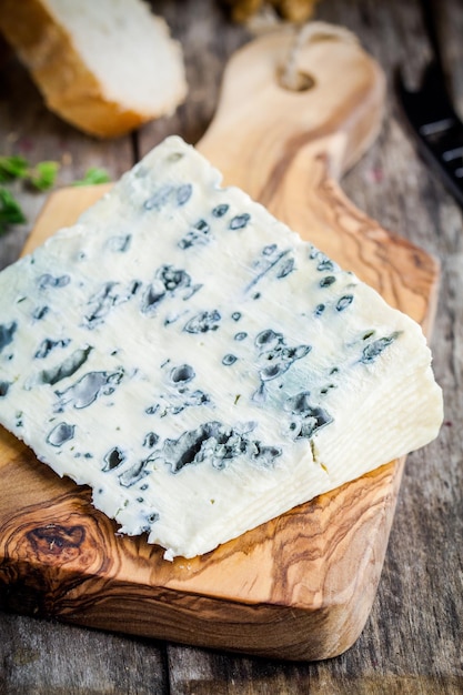 Blue cheese slice closeup on wooden cutting board