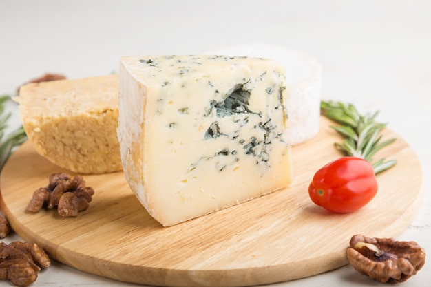 Blue cheese and various types of cheese on wooden board on a white background