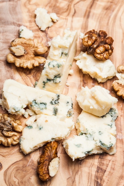 Blue cheese and walnuts close up on olive wooden board