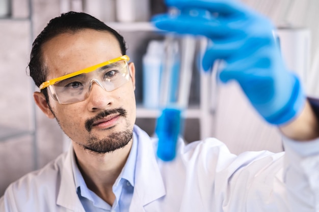 Blue chemical liquid experiment in scientific glassware\
equipment in science medicine laboratory chemistry or biology\
research discovery by using glass of test tube or beaker and\
flask