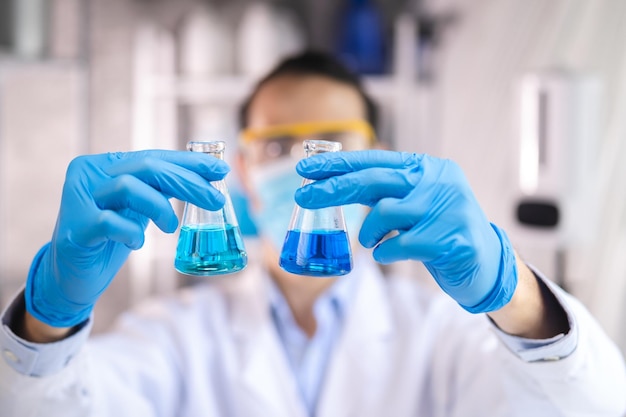 Photo blue chemical liquid experiment in scientific glassware equipment in science medicine laboratory chemistry or biology research discovery by using glass of test tube or beaker and flask