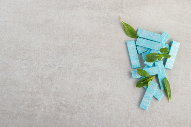 Blue chewing gums with mint leaves placed on a stone table .