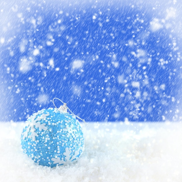 Blue Christmas ball on snowing background