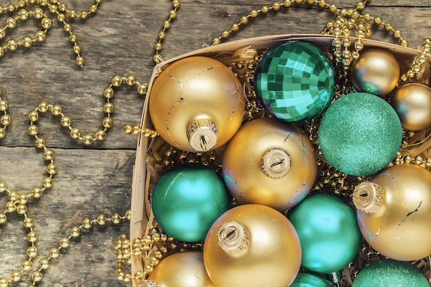 Голубые рождественские шары и золотые бусы лежат в деревянной корзине сверху в винтажном стиле