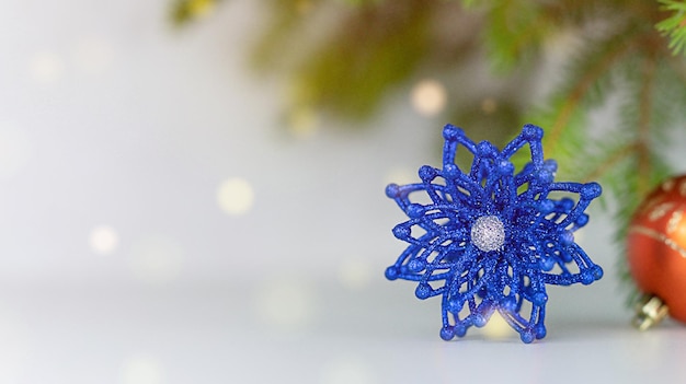 A blue Christmas toy on a background of spruce and golden bokeh lights. New Year backgrounds