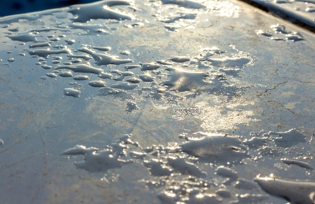 On a blue clad tile gleams a drop of water and ice in the sun