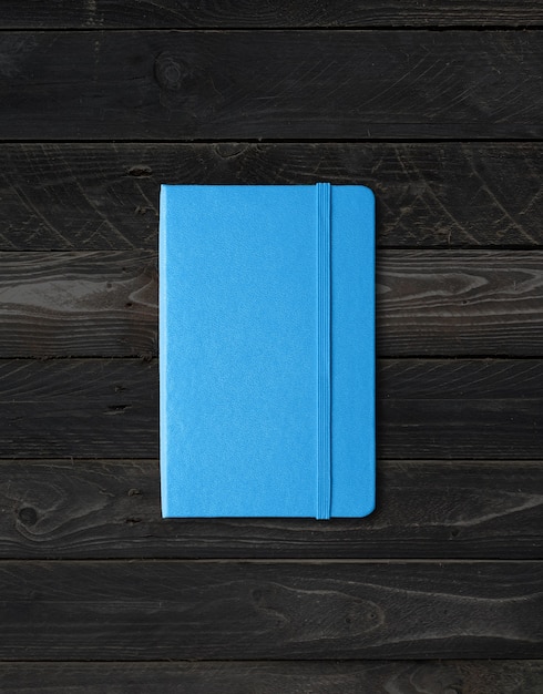 Blue closed notebook mockup isolated on black wood background