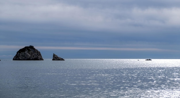 青い曇り空と海の空中ドローン ビュー無限の青の小さな岩の島々