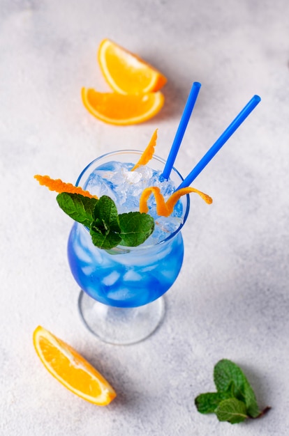 Blue cocktail drink with ice and orange