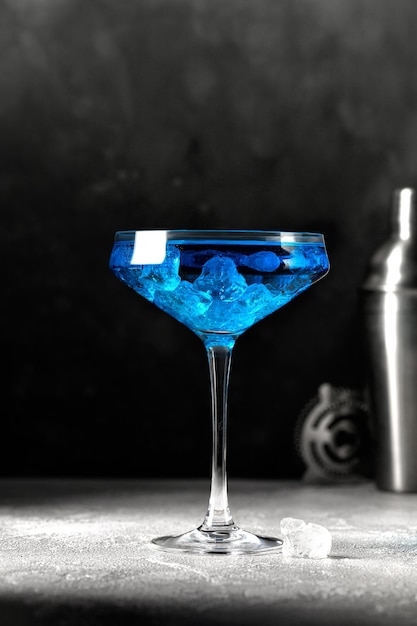 Blue cocktail in high glass with ice on grey background Blue lagoon Barmen equipment