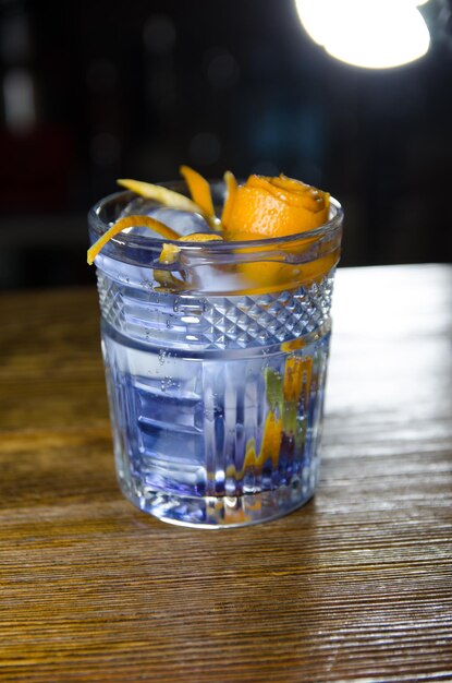 blue cocktail with gin and orange flowers on a wooden bar, halloween party invitation template