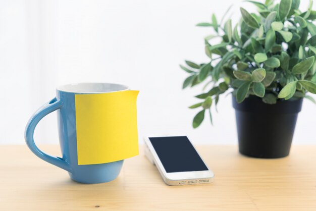 Foto tazza e nota di post-it di caffè blu sul piano d'appoggio di legno