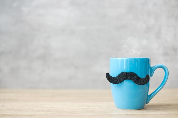 Blue coffee cup or tea mug with Black mustache decor on table Blank copy space for text Blue November Happy Father day and International men day concept