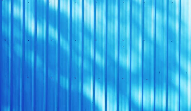 Фото Синий цвет гофрированного металлического цинкового листа текстуры фона с солнечным светом для дизайнерских работ и узорных обоев крупным планом