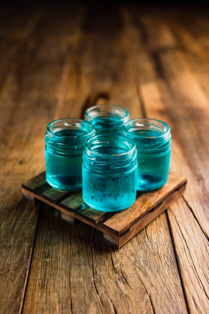 Blue colored alcoholic shooters, or shot drinks on wooden table