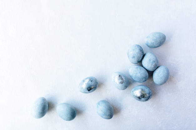 Blue Colored Eggs and flowers on light background