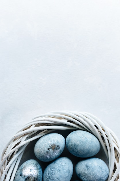 Photo blue colored eggs and flowers on light background