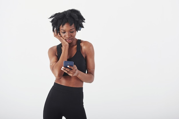 Blue colored smartphone in hands. Young beautiful afro american woman