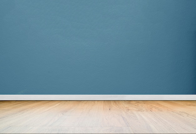 Blue concrete wall in empty room with wooden floor.