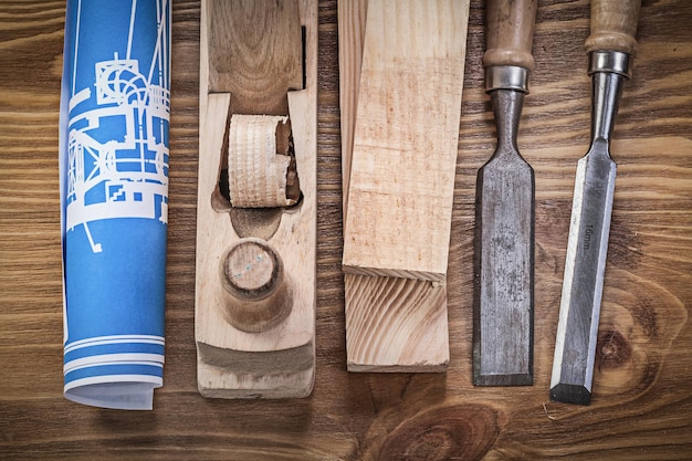 Blue construction plan shaving plane chisels wooden studs on wood board.