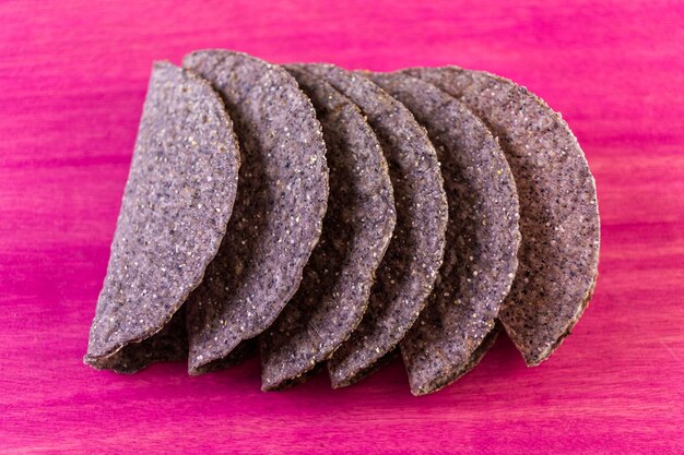 Blue corn taco shells on a pink background.