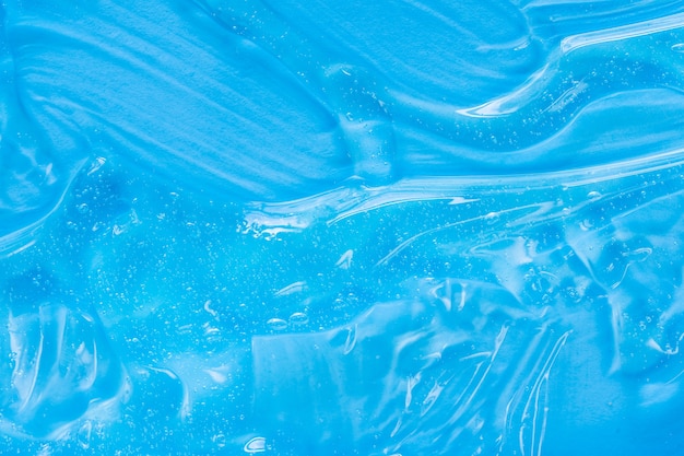 泡の透明なスキンケアクリームの顔の血清保湿剤の背景と青い化粧品のゲルの質感