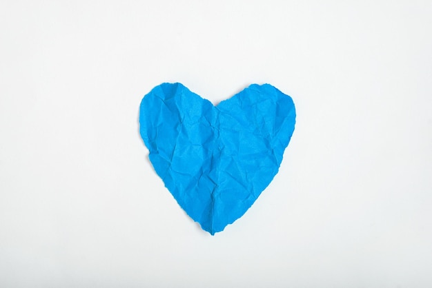 Blue crumpled paper texture in the shape of heart isolated on white background Concept of love