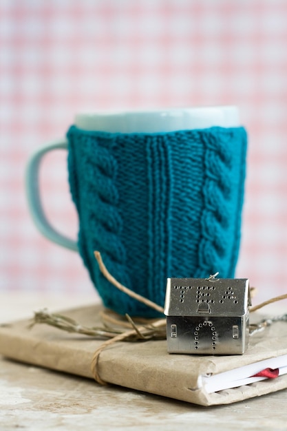 Blue cup in a blue sweater standing on an old notebook