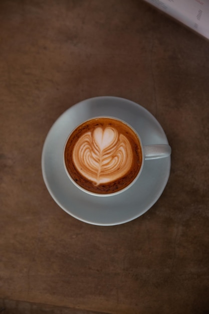 Blue cup of coffee on concrete rustic background with beautiful latte art