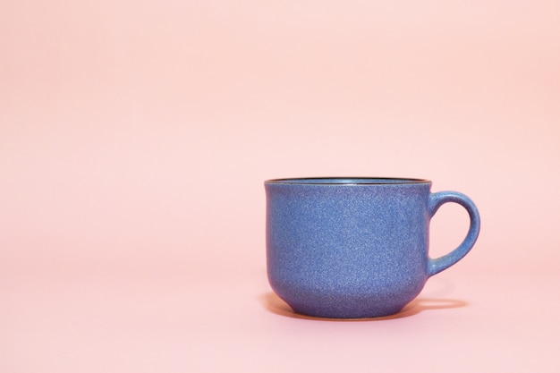 Голубая чашка кофе на розовом фоне