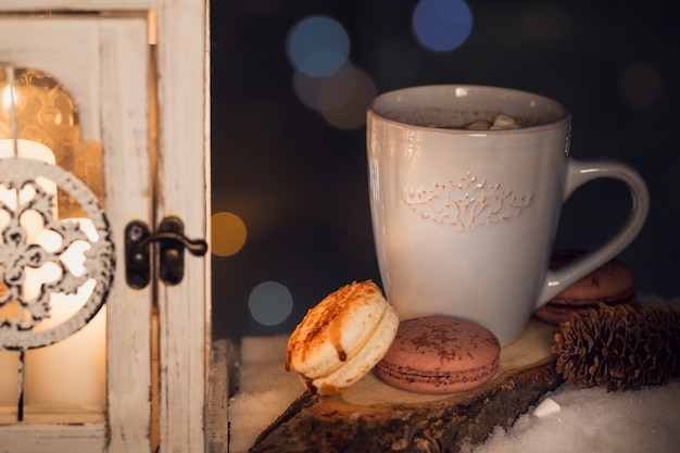 A blue cup with a hot drink and cookies in snow. Winter holidays concept.