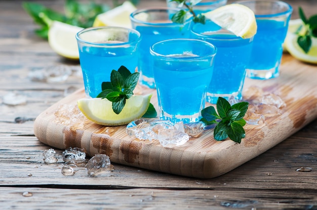 Liquore blu del curacao con il limone sulla tavola di legno