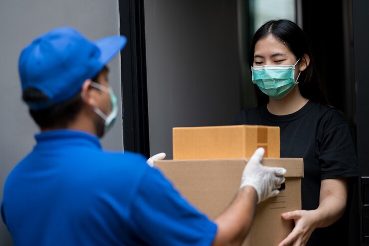 Photo 藍色配送員戴著保護面具將包裹送給客戶