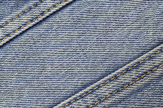 Blue denim background with diagonal stripes with stitches