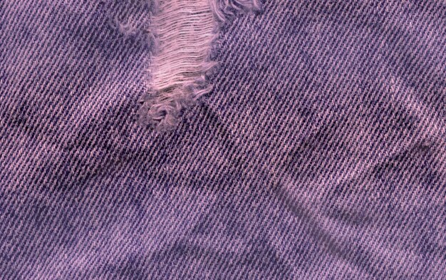 ブルーデニムジーンズテクスチャ背景。ジーンズの引き裂かれた布の質感