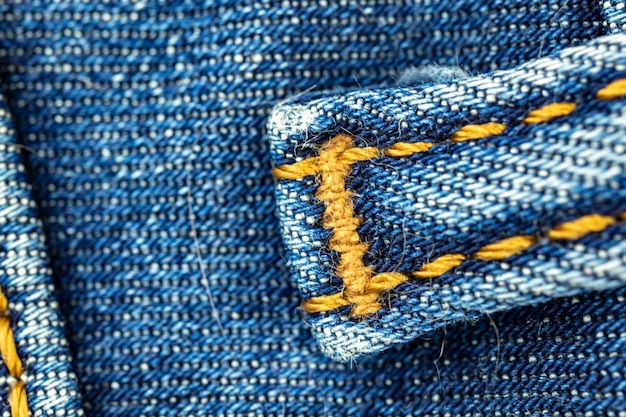 Blue denim jeans with orange thread stitches close-up, casual and urban classic fashion concept photo