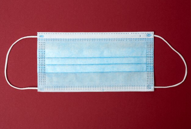 Blue disposable medical mask on a red background