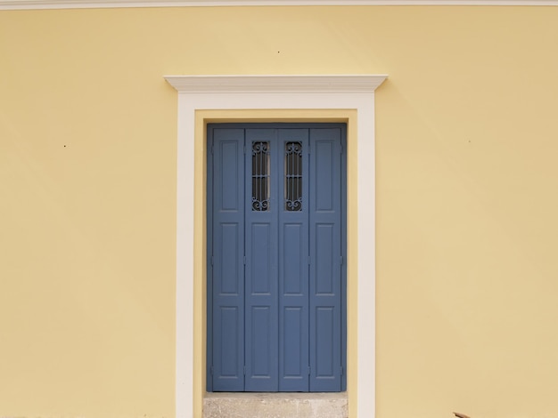 A blue door is on a yellow wall with a white frame.